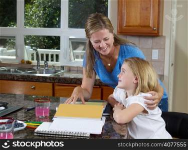 Front view of mom helping her younger daughter doing her homework while in the kitchen