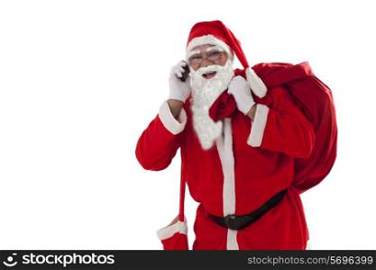 Front view of Santa Claus carrying sack while talking on cell phone