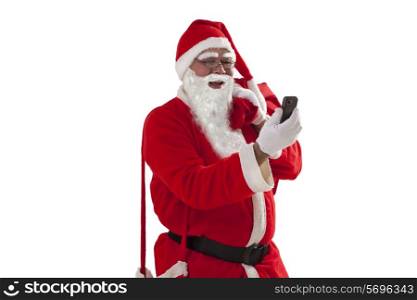 Front view of Santa Claus looking at mobile phone while carrying sack of Christmas presents