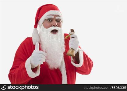 Front view of Santa Claus showing thumbs up while eating chocolate bar over white background