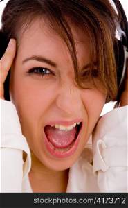 front view of screaming young woman listening music against white background