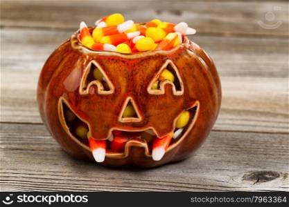 Front view of spooky pumpkin with candy fangs filled with candy corn on rustic wood. Halloween concept.