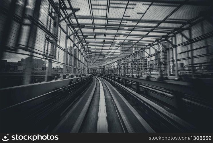 Front view of train moving in city rail tunnel with moderate motion blur in black and white filter. Transportation concept and motion blur background abstract.