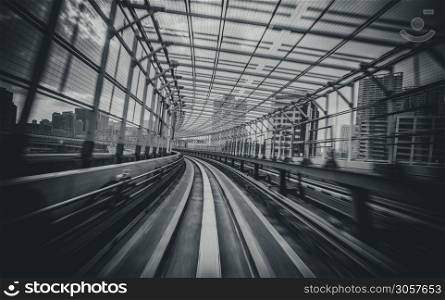 Front view of train moving in city rail tunnel with moderate motion blur in black and white filter. Transportation concept and motion blur background abstract.