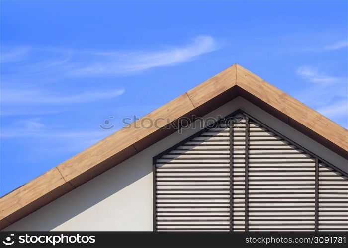 Front view of wooden gable roof with battens decoration of retro house against cloud on blue sky background