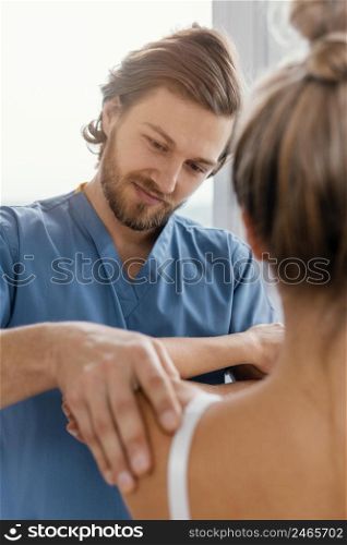 front view osteopathic therapist checking female patient s shoulder