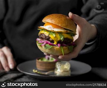 front view person holding burger with fried egg