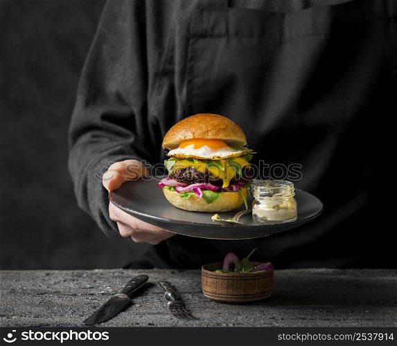 front view person holding plate with burger