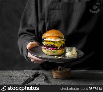 front view person holding plate with burger