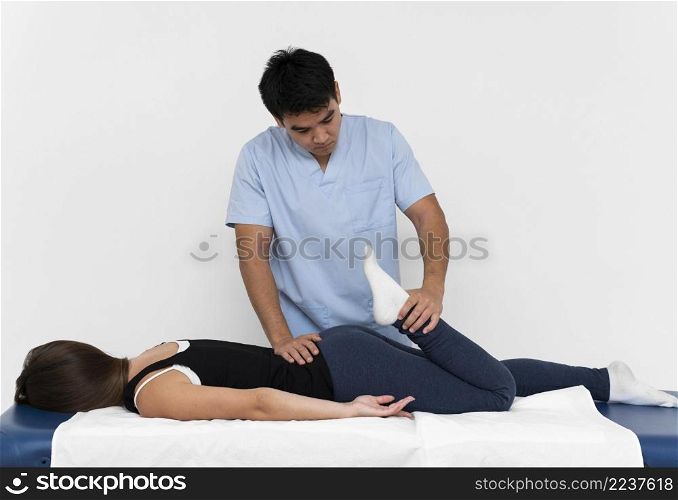 front view physiotherapist doing leg exercises with woman