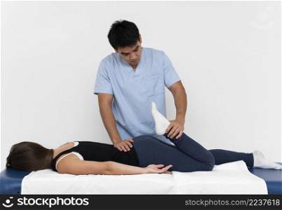 front view physiotherapist doing leg exercises with woman