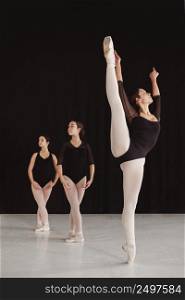 front view professional ballet dancers practicing together while wearing pointe shoes