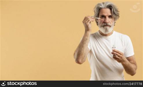 front view senior bearded man applying serum