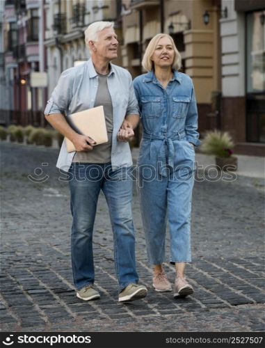 front view senior couple with tablet taking walk city