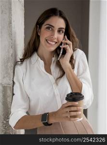 front view smiley businesswoman talking phone while having coffee