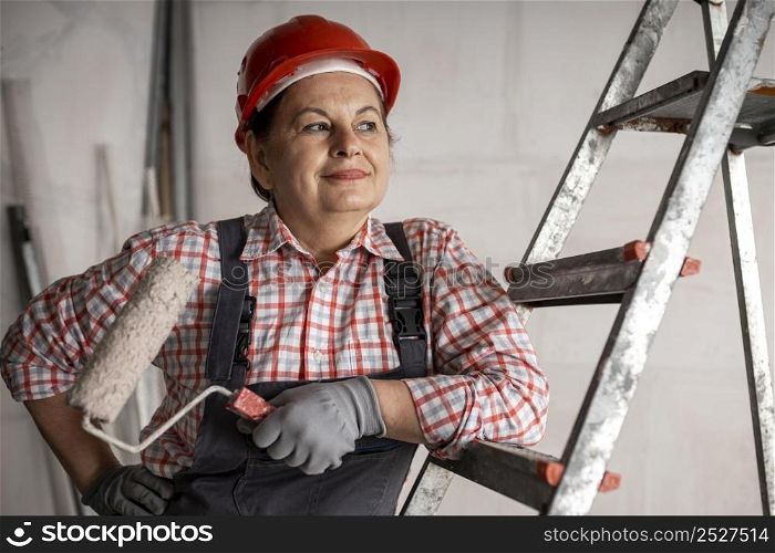 front view smiley female construction worker with paint roller