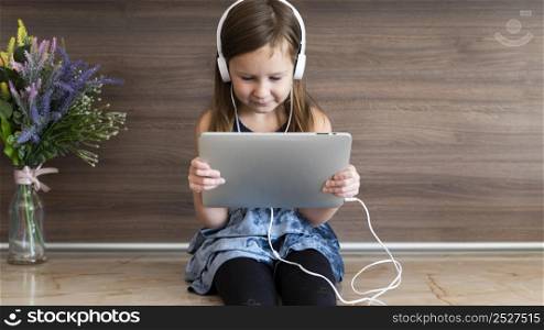 front view smiley girl using tablet with headphones