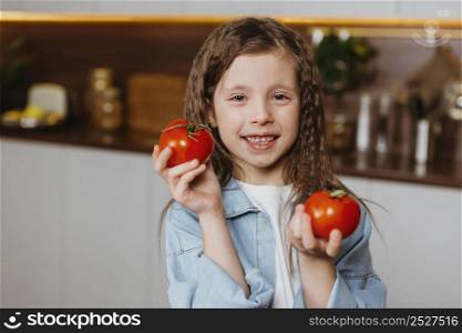 front view smiley little girl kitchen with tomatoes