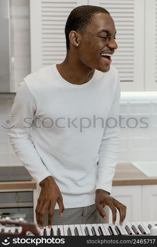 front view smiley male musician home playing electric keyboard