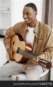 front view smiley male musician home playing guitar 2