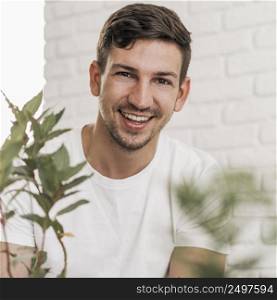 front view smiley man sitting plants
