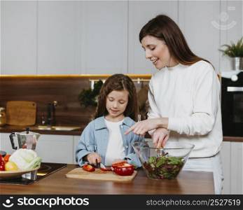 front view smiley mother daughter preparing food kitchen