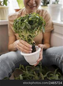front view smiley woman holding pot plant