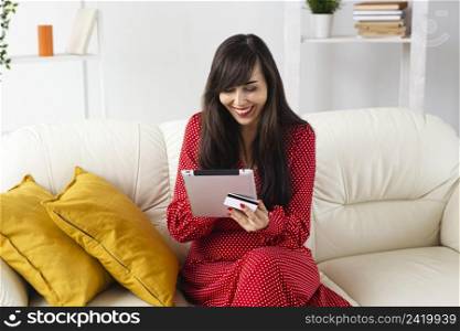 front view smiley woman home ordering items sale using tablet credit card