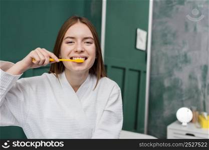 front view smiling woman brushing her teeth