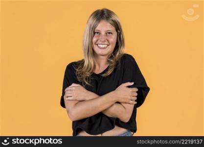 front view smiling young woman hugging her self yellow surface