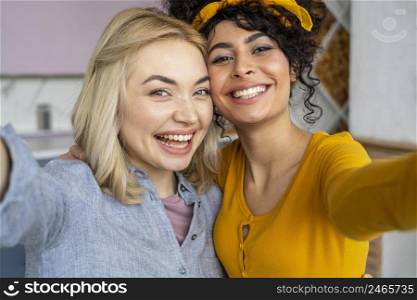 front view two smiley women taking selfie