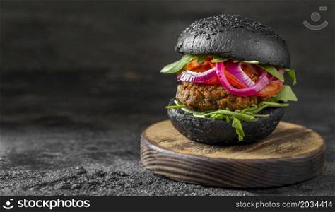 front view veggie burger with black buns cutting board