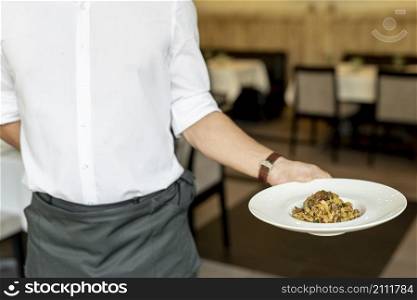 front view waiter holding plate with pasta