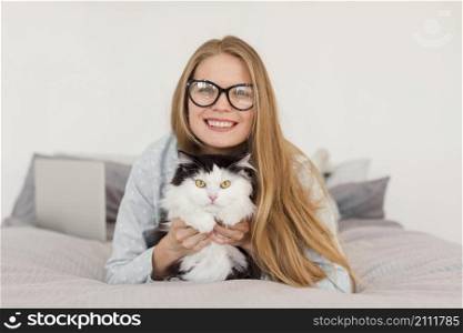front view woman bed wearing pajamas with cat laptop