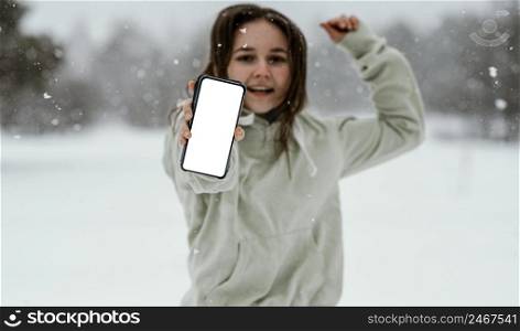 front view woman holding smartphone jumping air outdoors winter
