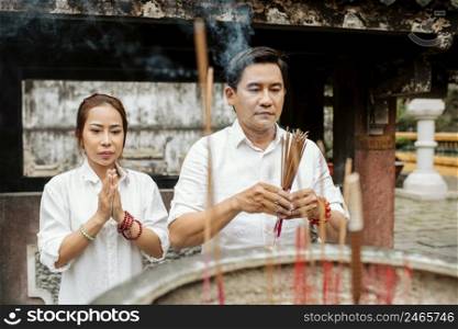 front view woman man praying temple with burning incense