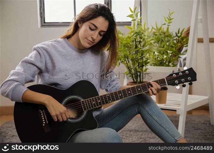 front view woman playing guitar home