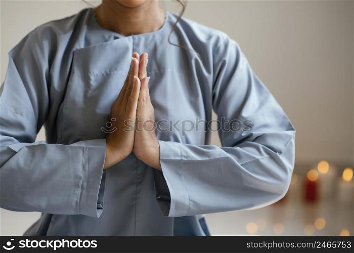 front view woman praying with candles