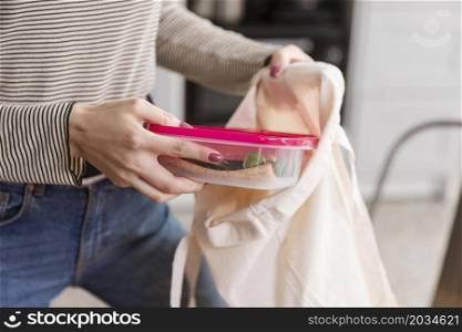 front view woman puts lunch boxes bag