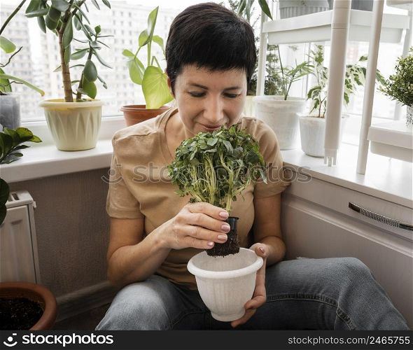 front view woman smelling indoor plant