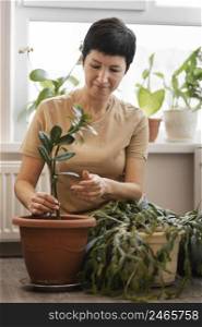 front view woman tending indoor plant