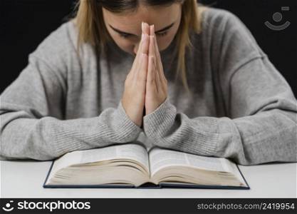 front view woman with bible praying