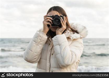 front view woman with camera beach