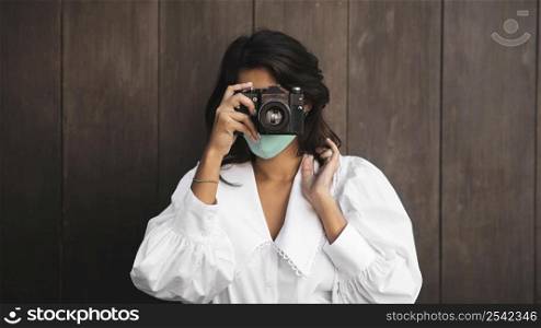 front view woman with face mask using camera