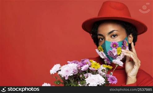 front view woman with mask posing with flowers