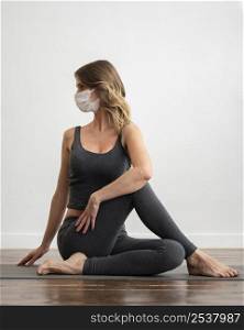 front view woman with medical mask doing yoga home