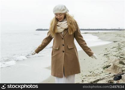front view woman with mittens beach during winter