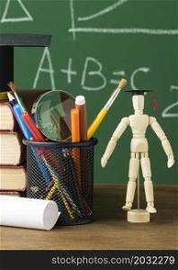 front view wooden figurine with academic cap books
