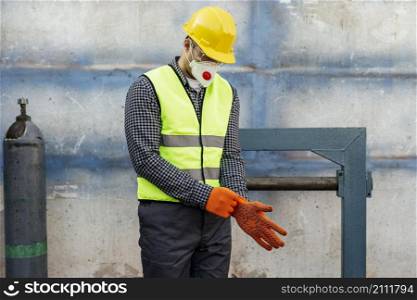 front view worker with hard hat putting protective gloves