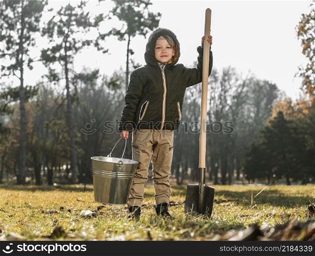 front view young boy outdoors holding bucket shovel